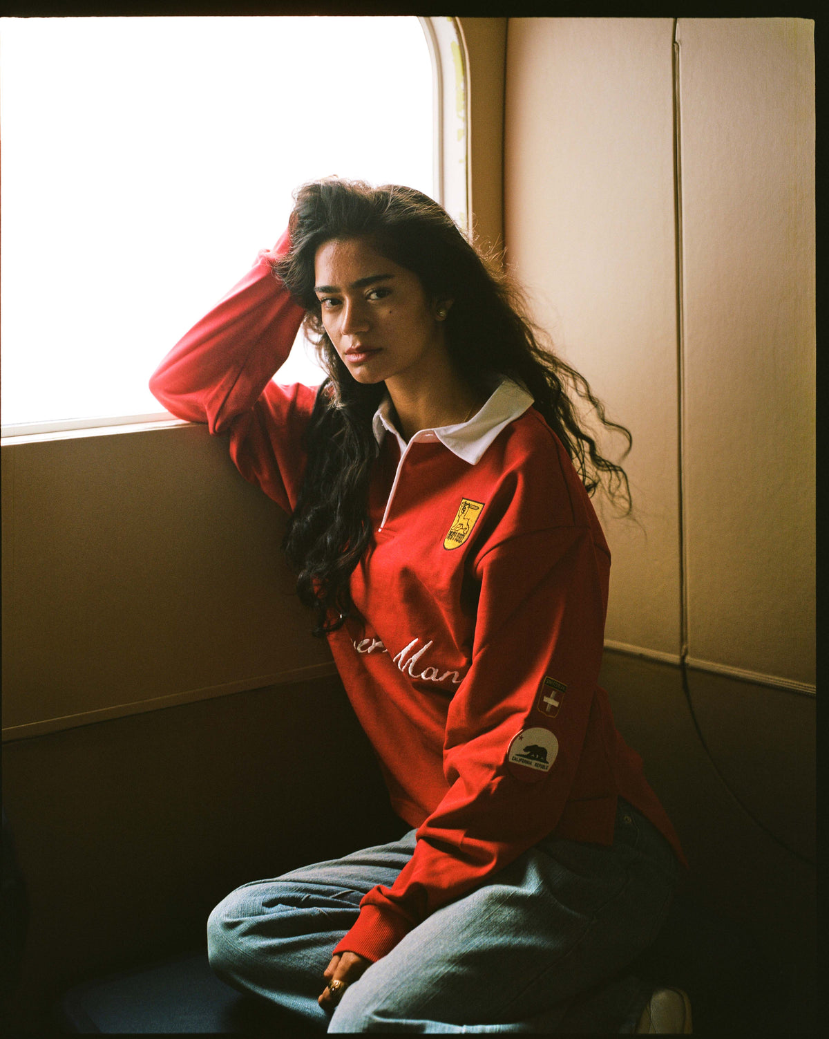 A woman in the red rugby by a cabin window