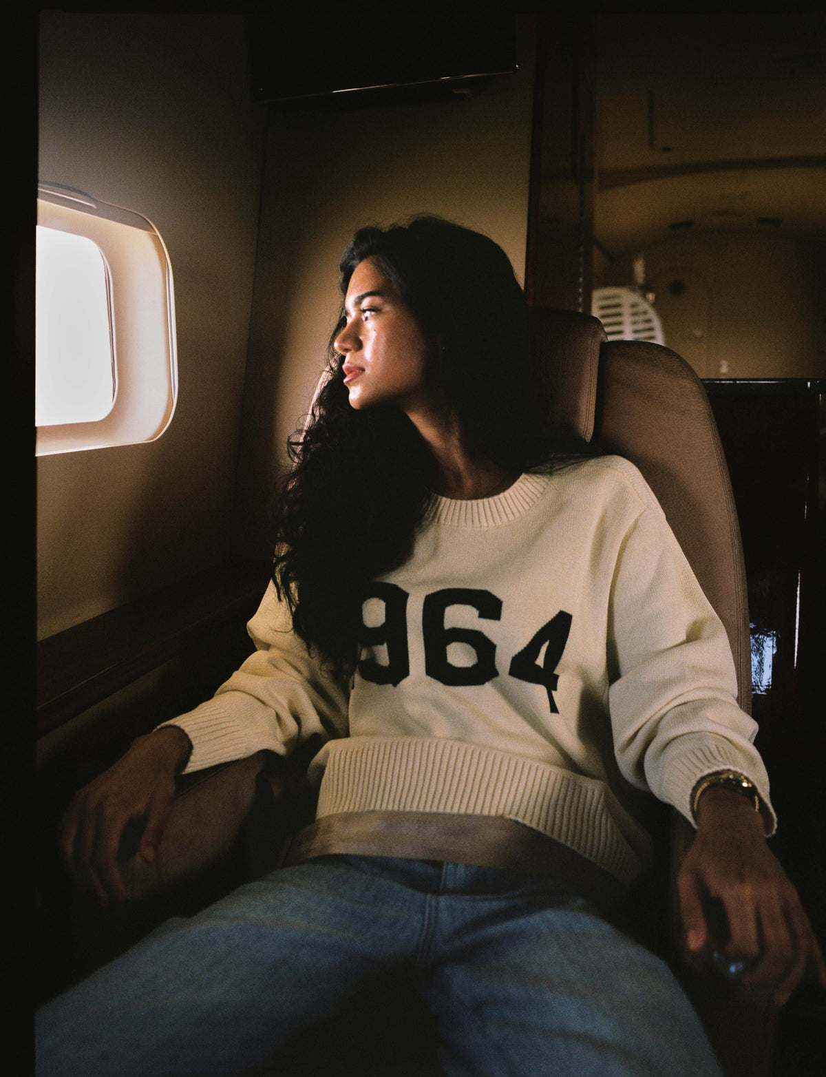 A woman in the cream 1964 sweater in a cabin seat
