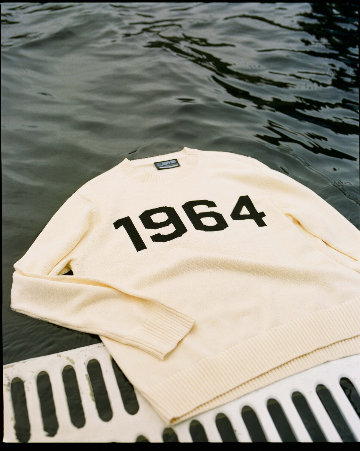 The cream 1964 sweater laid out by the water